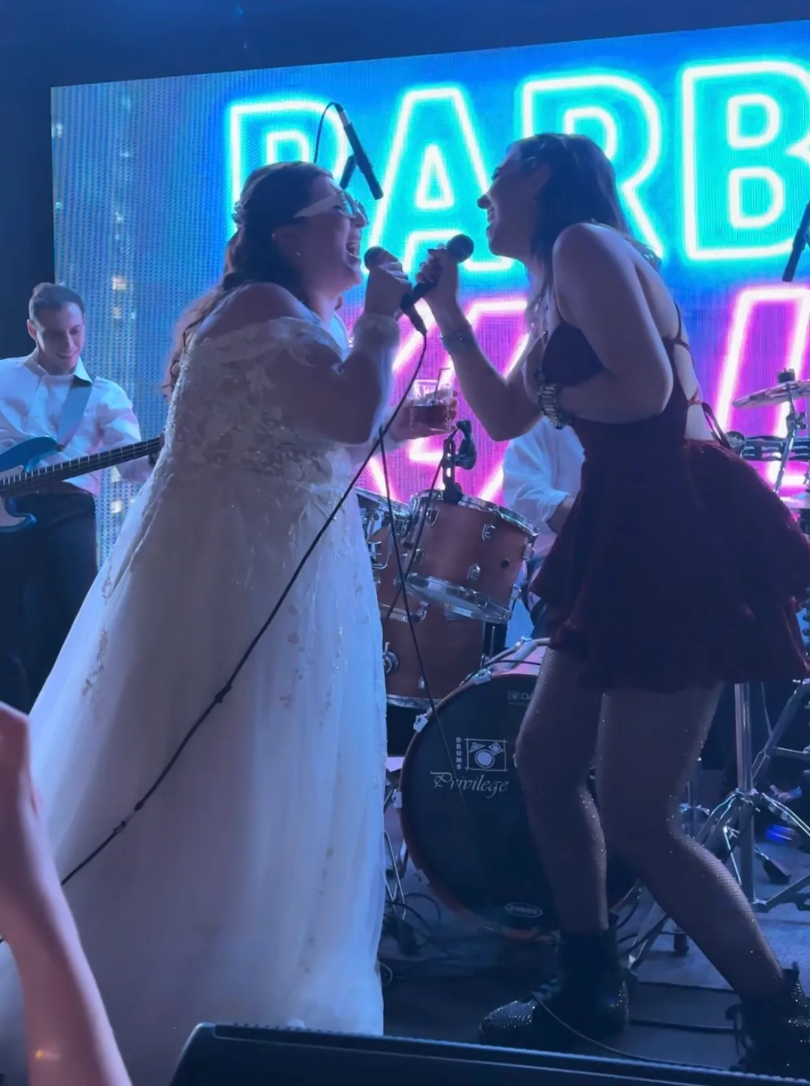 Noiva e vocalista da banda cantando juntas no palco